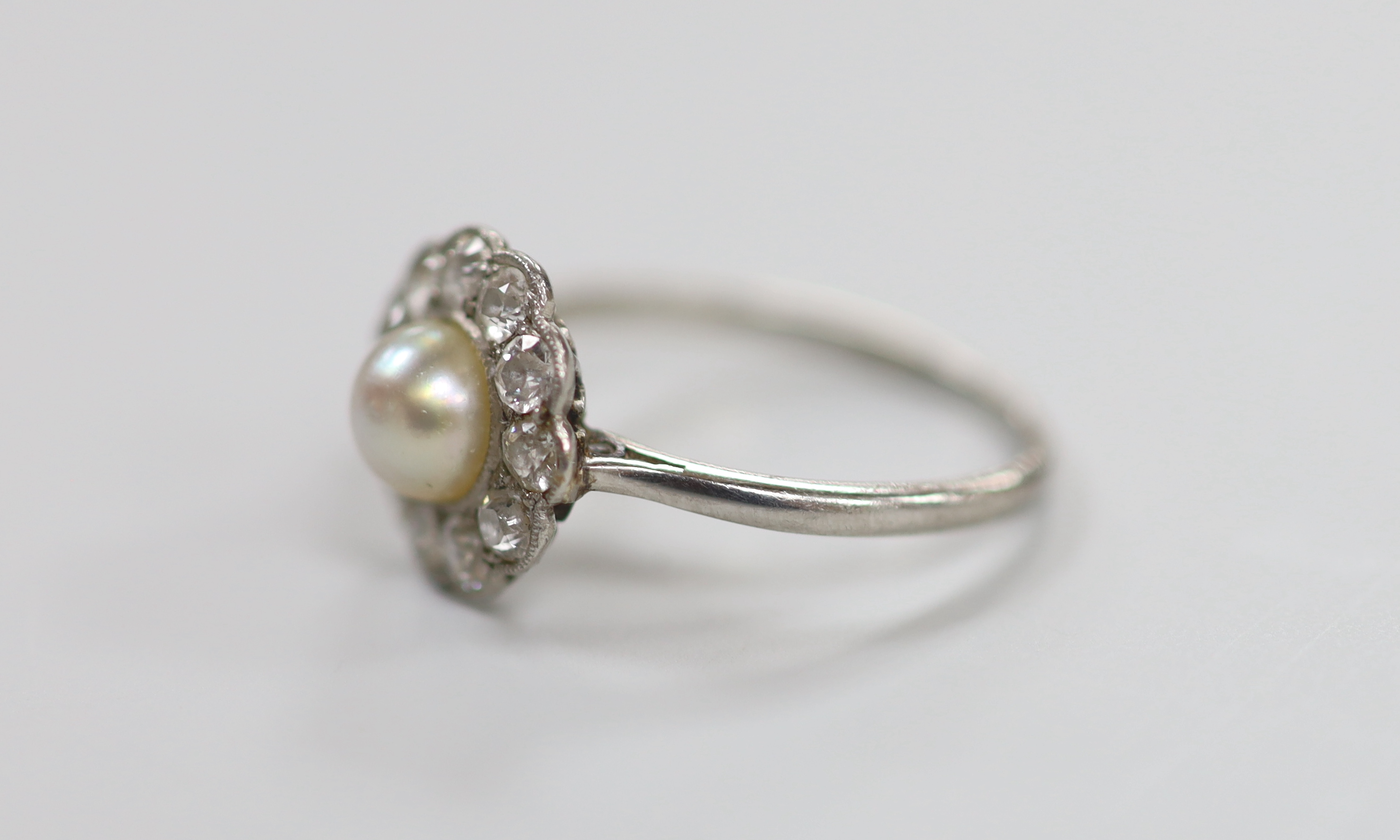 A 1920's white metal, cultured pearl and diamond set circular cluster ring, size M/N, gross weight 3.3 grams.